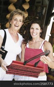 Portrait of a mid adult woman and her mother choosing a hand bag and smiling