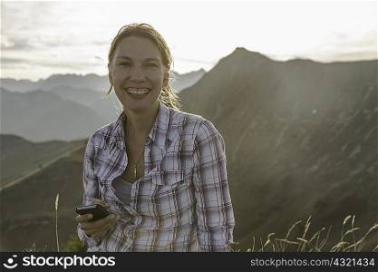 Portrait of a mid adult woman backpacker with cellphone, Achensee, Tyrol, Austria