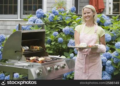 Portrait of a mid adult woman barbecuing in a lawn