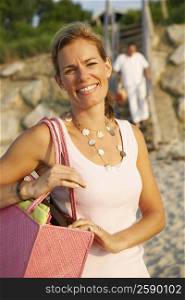 Portrait of a mid adult woman carrying a bag and smiling on the beach