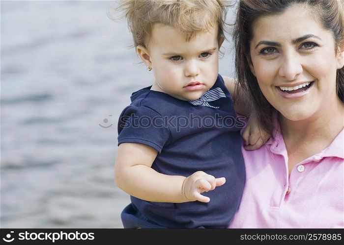 Portrait of a mid adult woman carrying her son and smiling