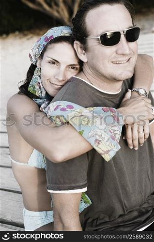 Portrait of a mid adult woman embracing a mid adult man from behind and smiling