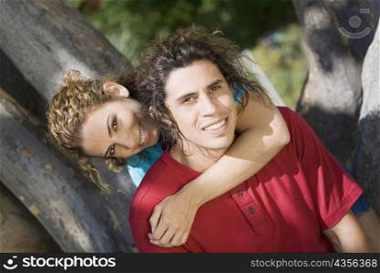 Portrait of a mid adult woman embracing a mid adult man from behind and smiling