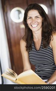 Portrait of a mid adult woman holding a book and smiling