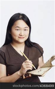 Portrait of a mid adult woman holding a book with a pencil and smiling