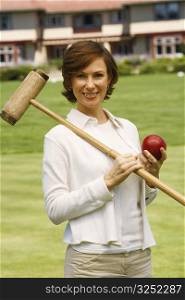Portrait of a mid adult woman holding a croquet mallet and a ball