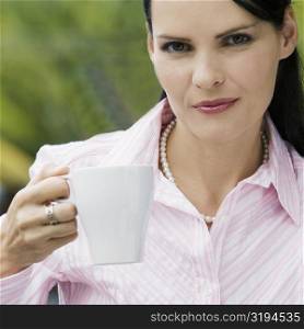 Portrait of a mid adult woman holding a cup of coffee and smiling