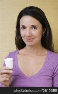 Portrait of a mid adult woman holding a cup of mouthwash