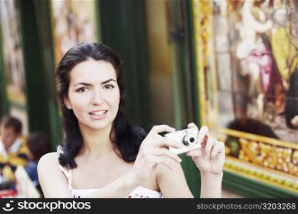 Portrait of a mid adult woman holding a digital camera