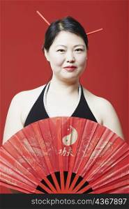 Portrait of a mid adult woman holding a folding fan