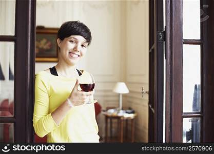 Portrait of a mid adult woman holding a glass of red wine and smiling
