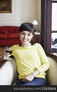 Portrait of a mid adult woman holding a glass of red wine and smiling