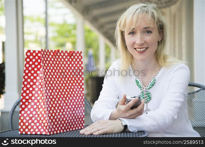Portrait of a mid adult woman holding a mobile phone and smiling