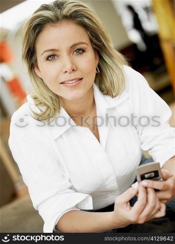 Portrait of a mid adult woman holding a mobile phone and smiling