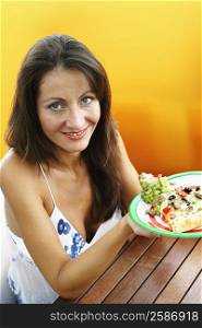 Portrait of a mid adult woman holding a plate of food