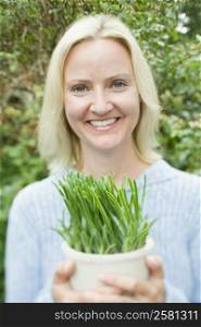 Portrait of a mid adult woman holding a potted plant and smiling