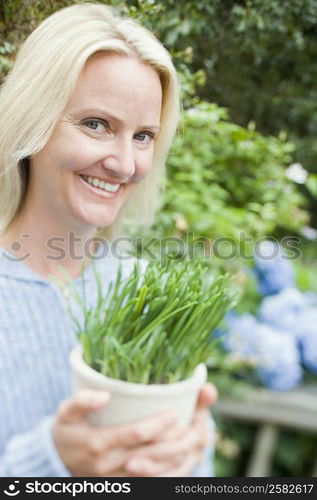 Portrait of a mid adult woman holding a potted plant and smiling