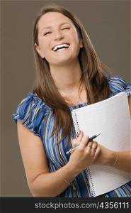 Portrait of a mid adult woman holding a spiral notebook and smiling