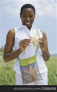 Portrait of a mid adult woman holding a starfish and smiling