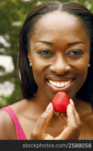 Portrait of a mid adult woman holding a strawberry and smiling