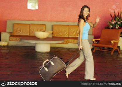 Portrait of a mid adult woman holding a suitcase and walking