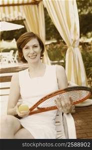 Portrait of a mid adult woman holding a tennis ball and a tennis racket
