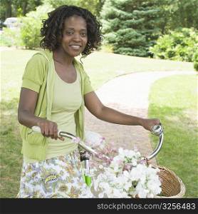Portrait of a mid adult woman holding Bicycle and smiling in a garden