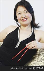 Portrait of a mid adult woman holding chopsticks