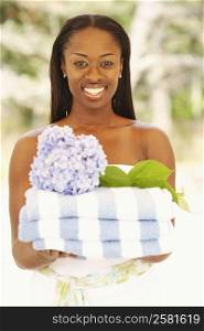 Portrait of a mid adult woman holding folded towels and a flower