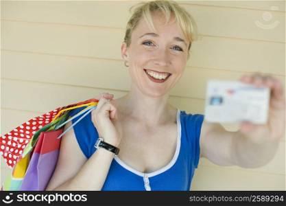 Portrait of a mid adult woman holding shopping bags and showing a credit card