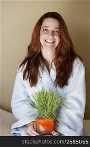 Portrait of a mid adult woman holding wheatgrass and smiling
