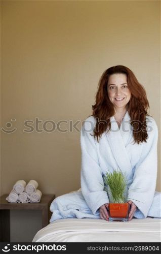 Portrait of a mid adult woman holding wheatgrass on a massage table