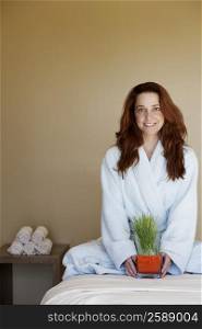 Portrait of a mid adult woman holding wheatgrass on a massage table