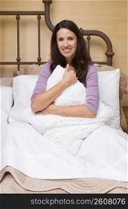 Portrait of a mid adult woman hugging a cushion and smiling
