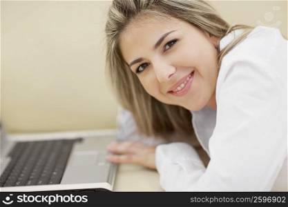 Portrait of a mid adult woman in front of a laptop and smiling