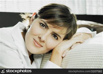 Portrait of a mid adult woman leaning against a bed