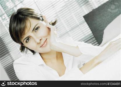 Portrait of a mid adult woman leaning against a bed with her hand on her chin