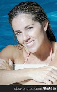 Portrait of a mid adult woman leaning at the poolside and smiling