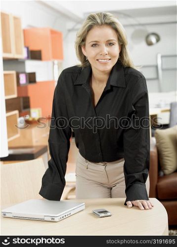 Portrait of a mid adult woman leaning on a table and smiling