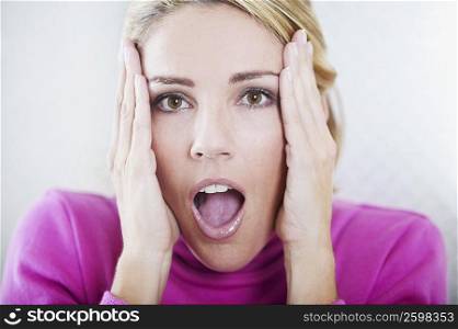 Portrait of a mid adult woman looking surprised with her head in her hands