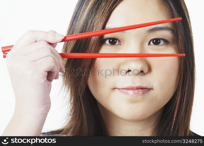 Portrait of a mid adult woman looking through chopsticks