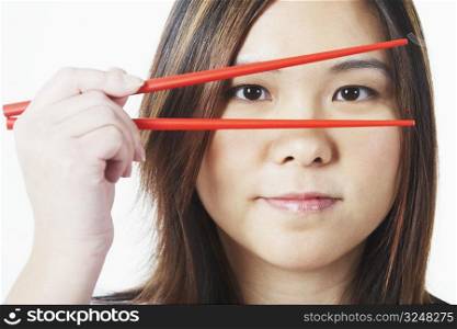 Portrait of a mid adult woman looking through chopsticks