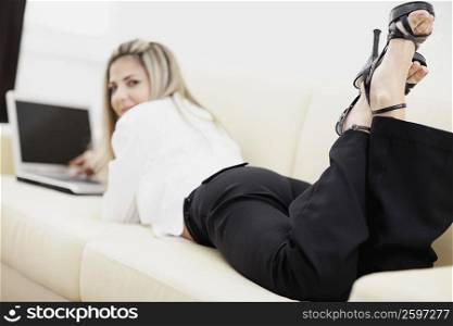 Portrait of a mid adult woman lying down and using a laptop