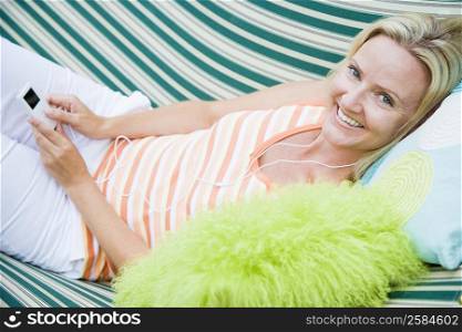 Portrait of a mid adult woman lying in a hammock and listening to an MP3 player