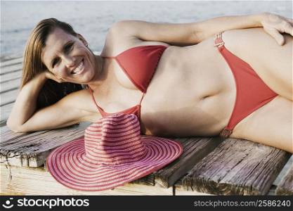 Portrait of a mid adult woman lying on a pier and smiling