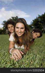 Portrait of a mid adult woman lying on grass with her two children