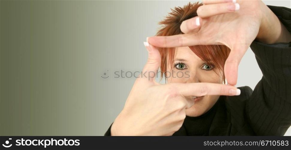 Portrait of a mid adult woman making a finger frame in front of her eyes