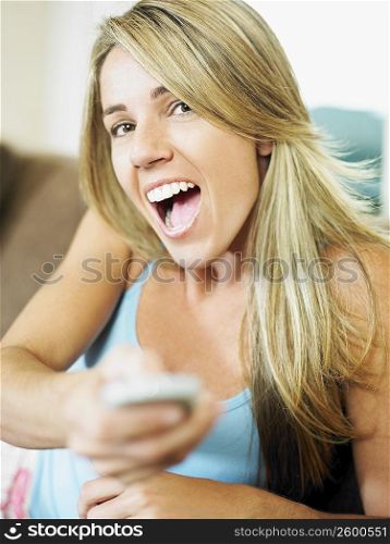 Portrait of a mid adult woman operating a remote control and laughing