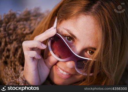 Portrait of a mid adult woman peeking over her sunglasses