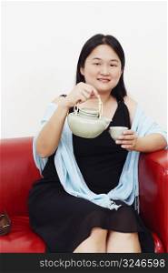 Portrait of a mid adult woman pouring tea from a kettle into the tea cup